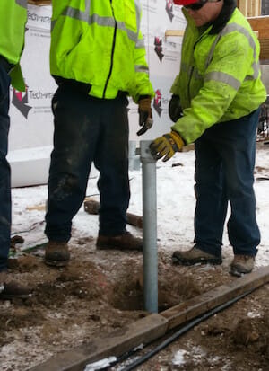 Kent's team is installing helical piers to support deck posts at a new construction site.