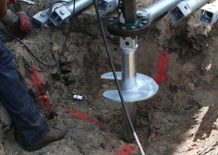 Photo of a crew member installing helical piers for foundation repair.